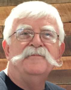 A man with white hair and mustache wearing glasses.